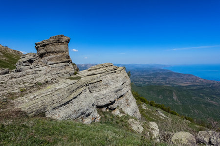 Ancient limestone high mountains of rounded shape in the air haze. The Valley of Ghosts. Demerji. Green trees and bushes in the foreground. May 2021. Crimea.の写真素材