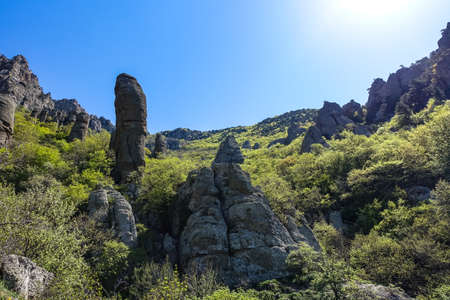 Ancient limestone high mountains of rounded shape in the air haze. The Valley of Ghosts. Demerji. Green trees and bushes in the foreground. May 2021. Crimea.の写真素材