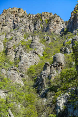 Ancient limestone high mountains of rounded shape in the air haze. The Valley of Ghosts. Demerji. Green trees and bushes in the foreground. May 2021. Crimea.の写真素材