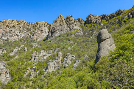 Ancient limestone high mountains of rounded shape in the air haze. The Valley of Ghosts. Demerji. Green trees and bushes in the foreground. May 2021. Crimea.の写真素材