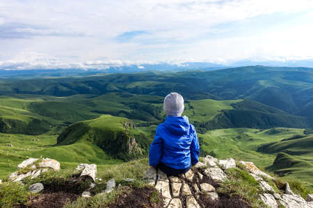 A little boy against the background of the mountains and the Bermamyt plateau in Russia. June 2021