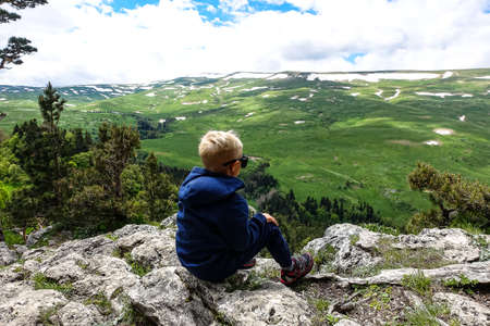A little boy on the background of the alpine meadows of the Lago-Naki plateau in Adygea. Russia.の写真素材