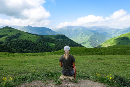 A girl on the background of a green landscape of the Aktoprak pass in the Caucasus. June 2021