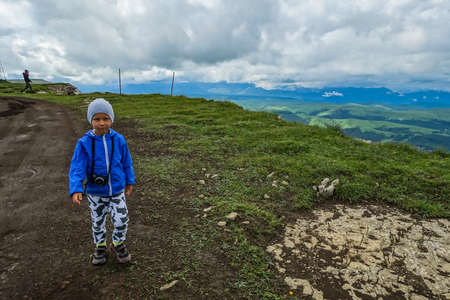 A little boy against the background of the mountains and the Bermamyt plateau in Russia. 2021