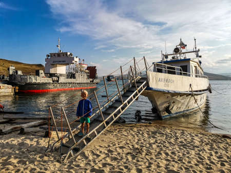 A boy on the background of boats and Lake Baikal in Listvyanka. Irkutsk Region 2020のeditorial素材