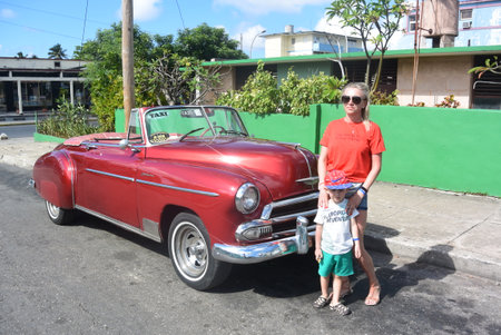 A girl with a child near a retro car on the streets of Varadero. Cuba 2019.のeditorial素材