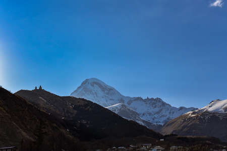 Holy Trinity Church in Gergeti on the background of mount Kazbek. Stepantsminda. Georgian military...