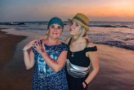 Mother and daughter on Ashwem beach with yellow sand, blue ocean and waves. Sunset North Goa, India 2020/のeditorial素材