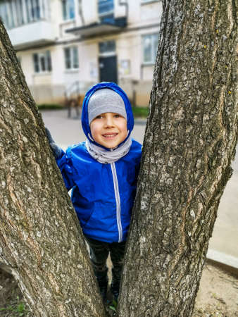 A small smiling boy between the trunks of a birch tree. Votkinsk Udmurtiaの写真素材