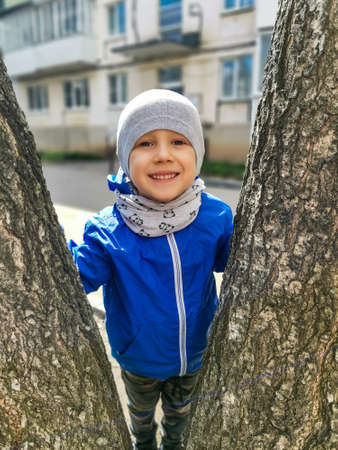 A small smiling boy between the trunks of a birch tree. Votkinsk Udmurtiaの写真素材