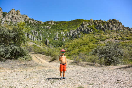 A little boy against the background of ancient limestone mountains of rounded shape . Demerdzhi. 2021. Crimea.の写真素材