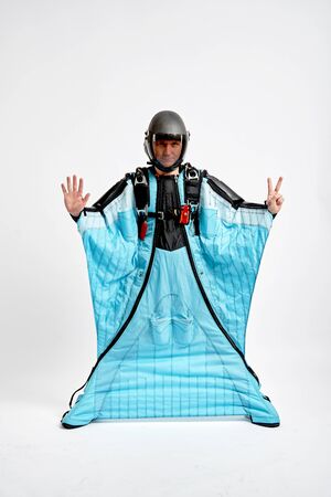 Eight fingers. Men in wing suit show eight fingers. Skydiving men in parashute. Simulator of free fall.の写真素材