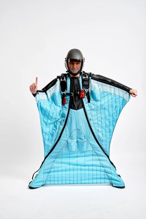 One finger. Men in wing suit show one finger. Skydiving men in parashute. Simulator of free fall.の写真素材