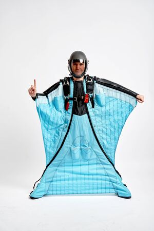 One finger. Men in wing suit show one finger. Skydiving men in parashute. Simulator of free fall.の写真素材