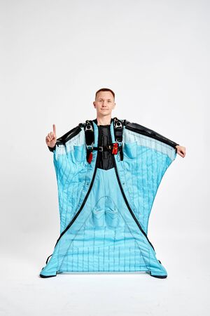 One finger. Men in wing suit show one finger. Skydiving men in parashute. Simulator of free fall.の写真素材