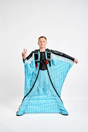 Three fingers. Men in wing suit show three fingers. Skydiving men in parashute. Simulator of free fall.の写真素材
