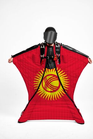 Kyrgyzstan flag travel. Simulator of free fall. Men in wing suit.の写真素材