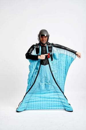 Finger in the side. Men in wing suit shows in the side by finger. Skydiving men in parashute. Simulator of free fall.の写真素材