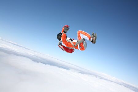 Risk. Fly men is a pilot of his body in air. Extreme people prefer skydiving. Parachutist in orange suit. Free lifestyle.の写真素材