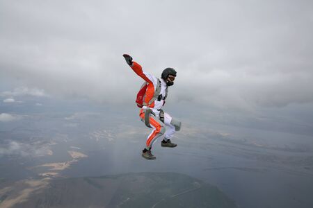 Skydiving. Fly men is a pilot of his body in air. Extreme people prefer skydiving. Parachutist in orange suit. Free lifestyle.の写真素材