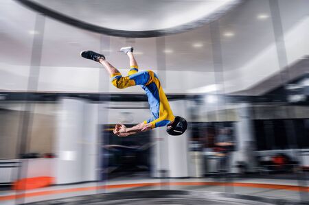 Hobbies. Skydiver is flying in wind tunnel. Extreme people in blue and yellow suit make air jump. Air sport as a way of life. Skydiving team.の写真素材