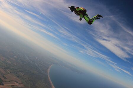 Skydiving. Fly men is a pilot of his body in air. Extreme people prefer skydiving. Parachutist in green suit. Free lifestyle.の写真素材