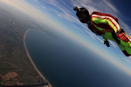 Journey. Flight speed of skydiver. Parachutist in green suit is in free fall. Extreme as a hobby.の写真素材