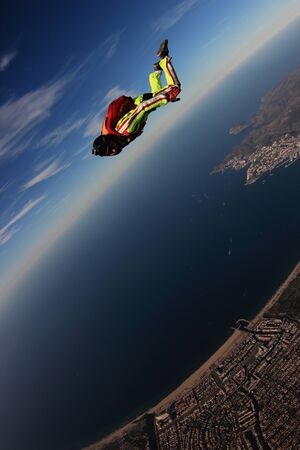 Activity. Men with parachute equipment have wings. Skydiver is flying in open air. Parachutist in blue suit is in free fall. No gravitation in sky.の写真素材