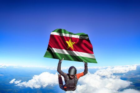 Surinam extreme. Flag in skydiving. People in free fall grab flag of Surinam. Patriotism, men and flag.の写真素材