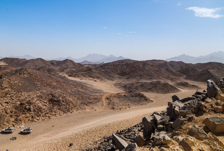 Brown sand, desert dunes and hills on blue sky background. Rough roads with vehicle tracks on dry, sandy land surface on sunny day.の写真素材