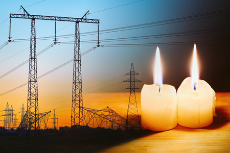 Burning flame candle and power lines on background. Energy outage and blackout. Energy crisis. Price increase of electricity for home and industry.の写真素材