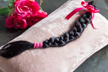 Brown hair braid on pink background for hair donation for women with cancer chemotherapy