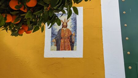 Yellow facade of a church with two tiles on its sides with the images of the Virgin and Jesus Christの写真素材