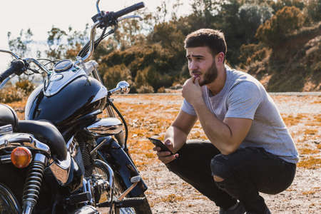 Crouching biker worried about a motorcycle breakdownの写真素材