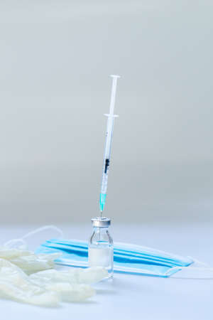 Vaccine vial, gloves, syringe and mask on white background, vertical