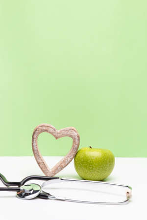 Apple, heart and stethoscope on vertical green and white backgroundの写真素材