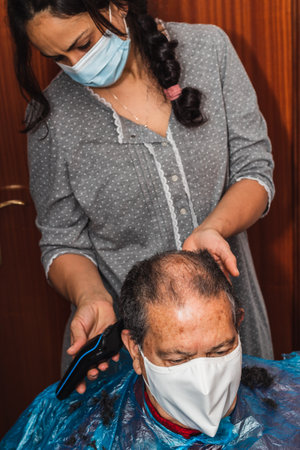 Daughter cutting her father's hair at homeの写真素材