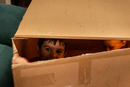 Child playing and looking through the crack of a cardboard boxの写真素材