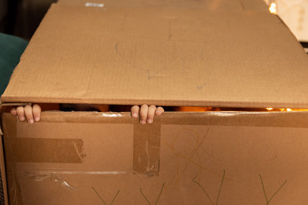 Child playing and looking through the crack of a cardboard box