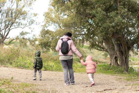 Mother and children walking in the field, unrecognizable