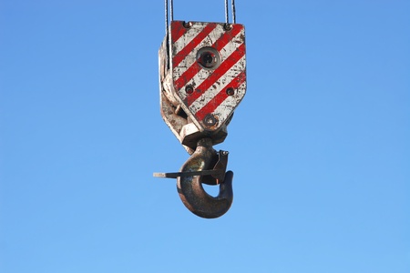 Detail of rusty crane hook and steel cables hanging on blue sky background