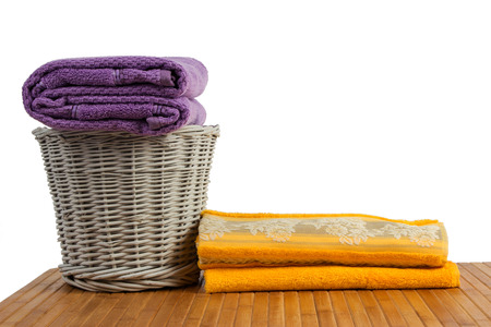 Wicker basket full of clean colored towels on a wooden table, on white backgroundの写真素材