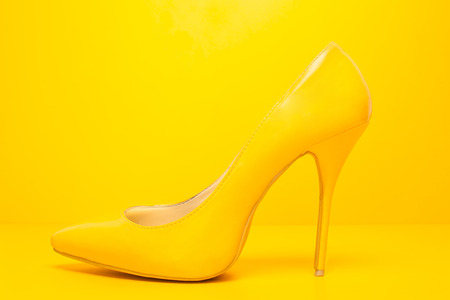 side view of high heels shoes on yellow backgroundの写真素材