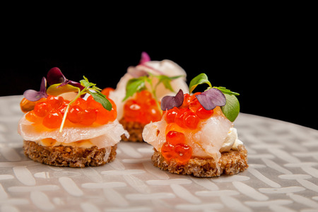 Appetizer of Salmon eggs, fish, and green herbs canapesの写真素材