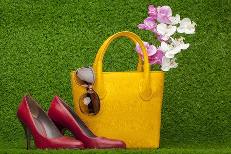 sunglasses, handbag and red shoes on green grassの写真素材
