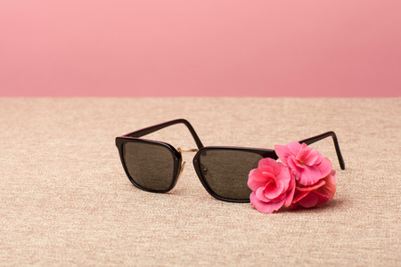 brown Sunglasses on canvas background an pink flowerの写真素材
