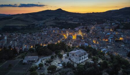 Aerial view with the Drone on Castellana Sicula, in the Madonie park at blue hour with the lights of the village on and the last sunset light on the skyの写真素材