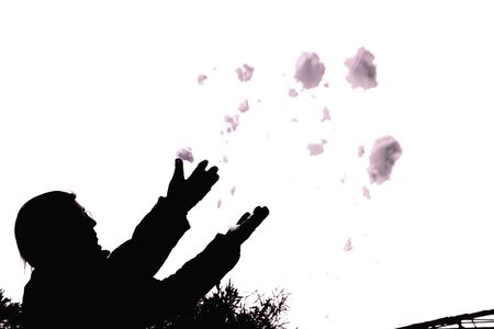 Silhouette of a woman playing with the snow throwing it in the air on white background