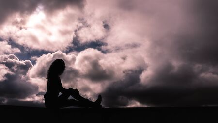 Young girl in silhouette on a cloudy skyの写真素材