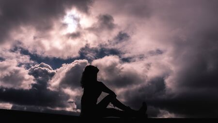 Young girl in silhouette on a cloudy skyの写真素材
